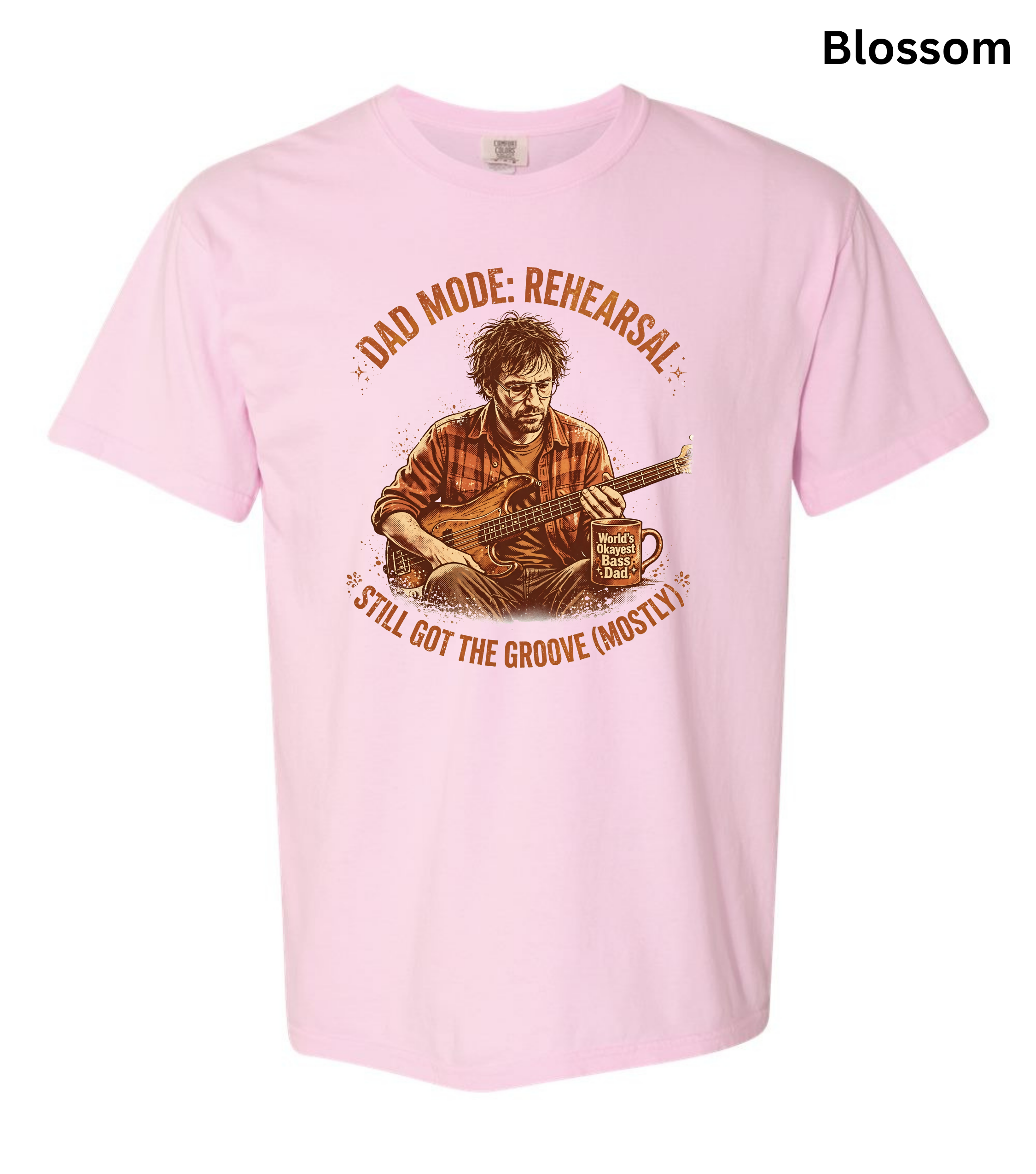 A light pink short-sleeve t-shirt with a vintage-style graphic of a man playing an acoustic guitar, surrounded by the text 'DAD MODE: REHEARSAL' and 'STILL GOT THE GROOVE (MOSTLY)'. The word 'Blossom' is printed in black in the top right corner.