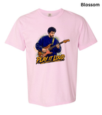 A light pink short-sleeve t-shirt with a graphic print of a man playing an electric guitar and the text 'PLAY IT LOUD' in yellow and black. The word 'Blossom' is printed in black in the top right corner.