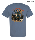 A blue short-sleeve graphic t-shirt on a white background, featuring a vintage-style illustration of a man playing an electric guitar with a microphone, surrounded by musical equipment. The text 'DAD MOSE, ROCKSTAR' is arched above the illustration, and 'STILL GOT THE GROOVE MASTERY!' is written below.