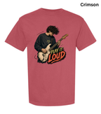A crimson short-sleeve t-shirt with a graphic of a guitarist playing an electric guitar next to the text 'PLAY IT LOUD' in orange and black. The word 'Crimson' is printed in black in the top right corner.