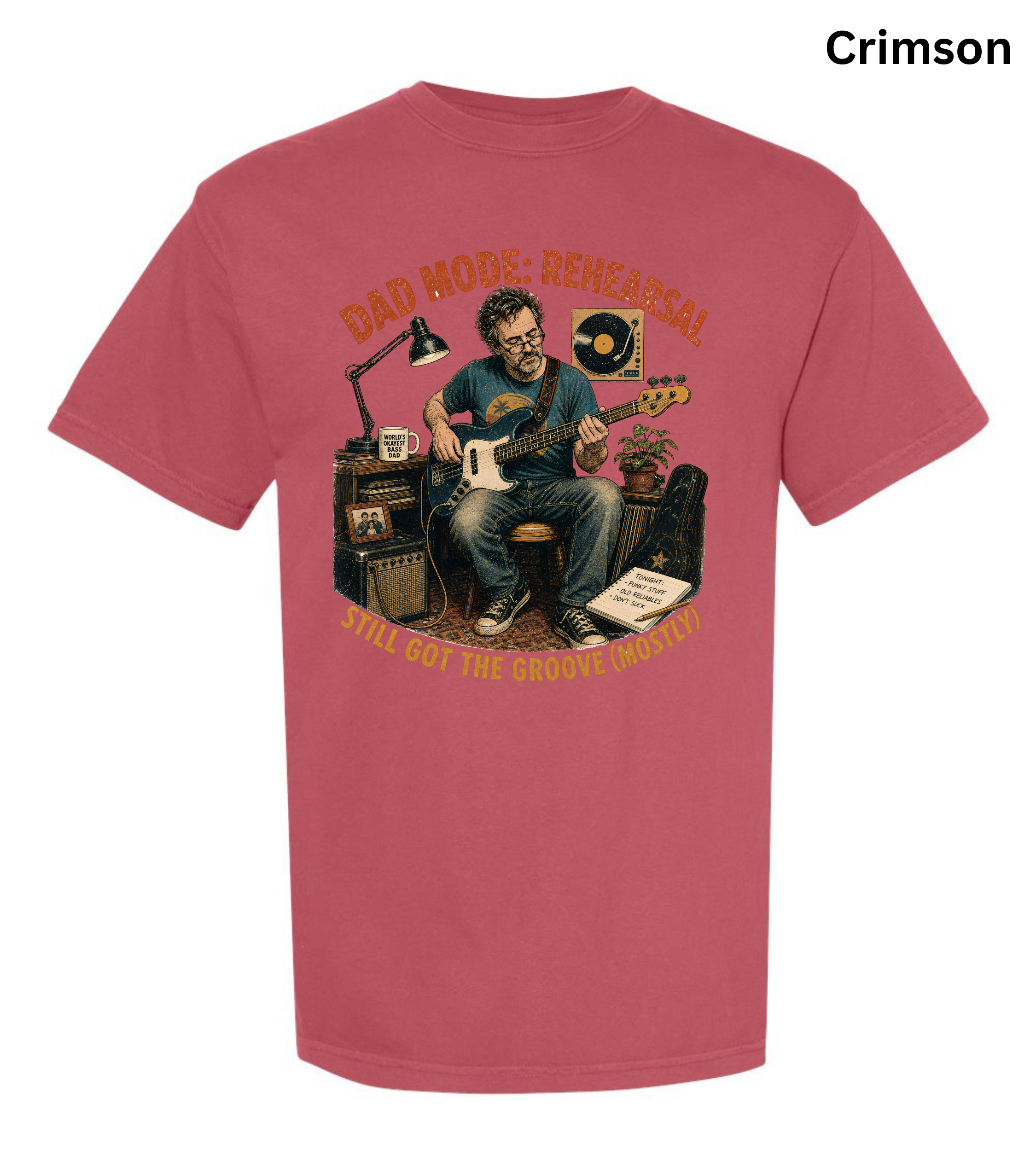 A short-sleeve crewneck t-shirt in a vibrant crimson color, featuring a large graphic print of a man playing an electric guitar surrounded by music equipment. The graphic includes the text 'DAD MODE - RESEARCH' at the top and 'I'LL GOT THE GROOVE (MUST!)' at the bottom.