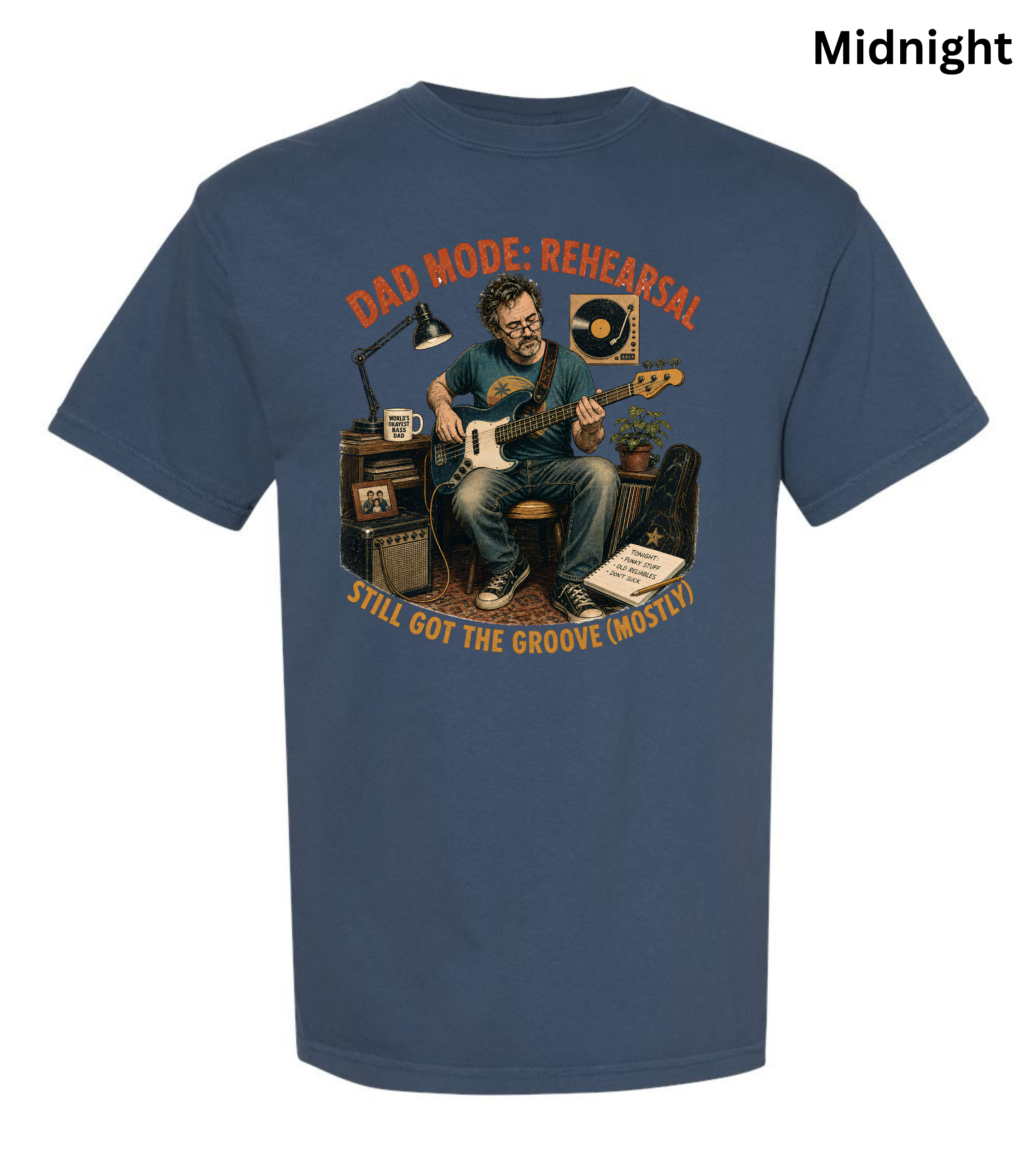 A navy blue short-sleeve t-shirt with a vintage-style graphic of a man playing an electric guitar in a rehearsal room. The graphic features the text 'DAD MODE: REHEARSAL' in orange at the top and 'STILL GOT THE GROOVE MOSTLY' in yellow at the bottom.