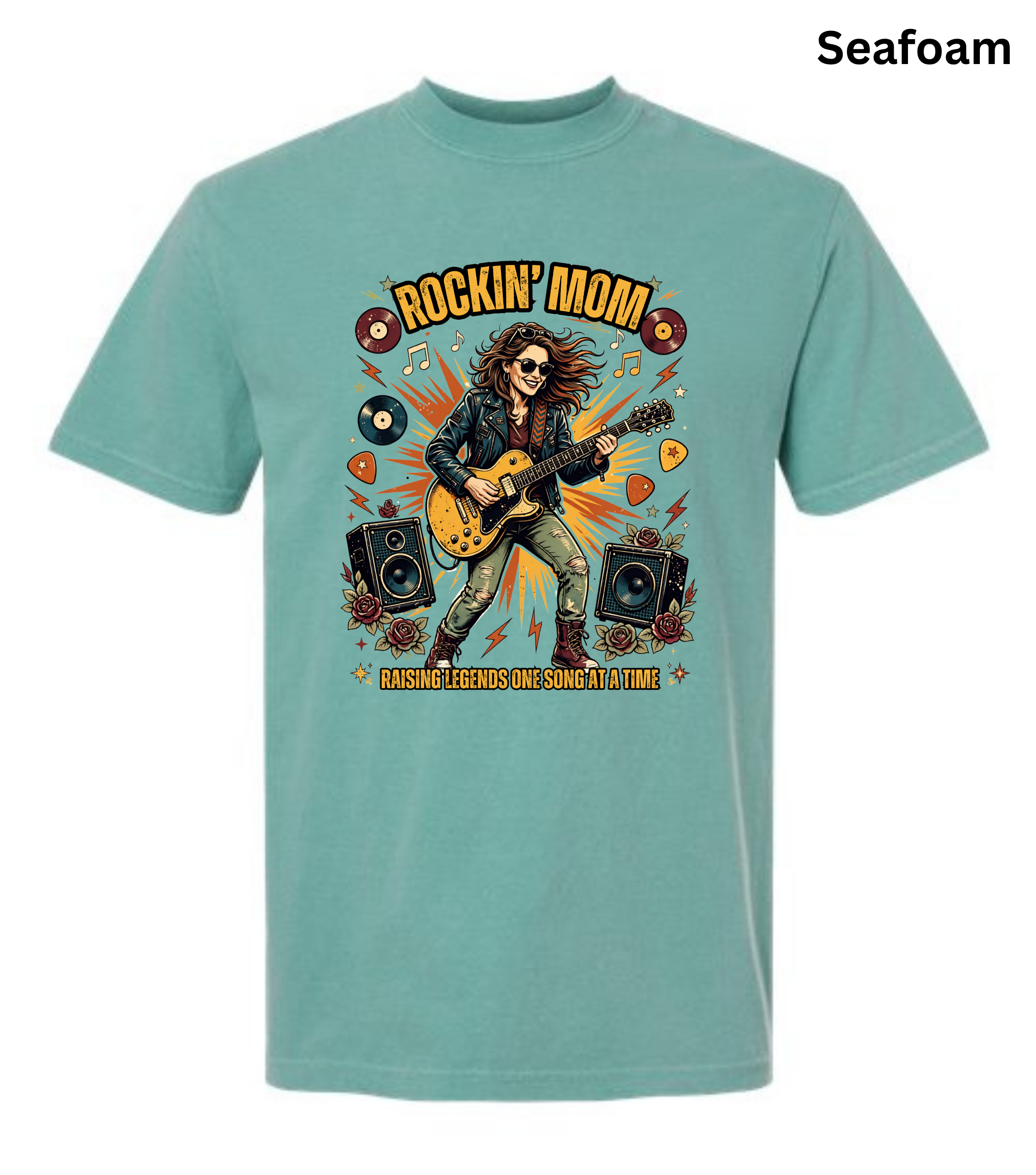 A seafoam green short-sleeve t-shirt with a colorful graphic of a woman playing an acoustic guitar, surrounded by vinyl records, speakers, and guitar picks, with the text 'ROCKIN' MOM' and 'CASHING OUT IS SINGING A LITTLE'.