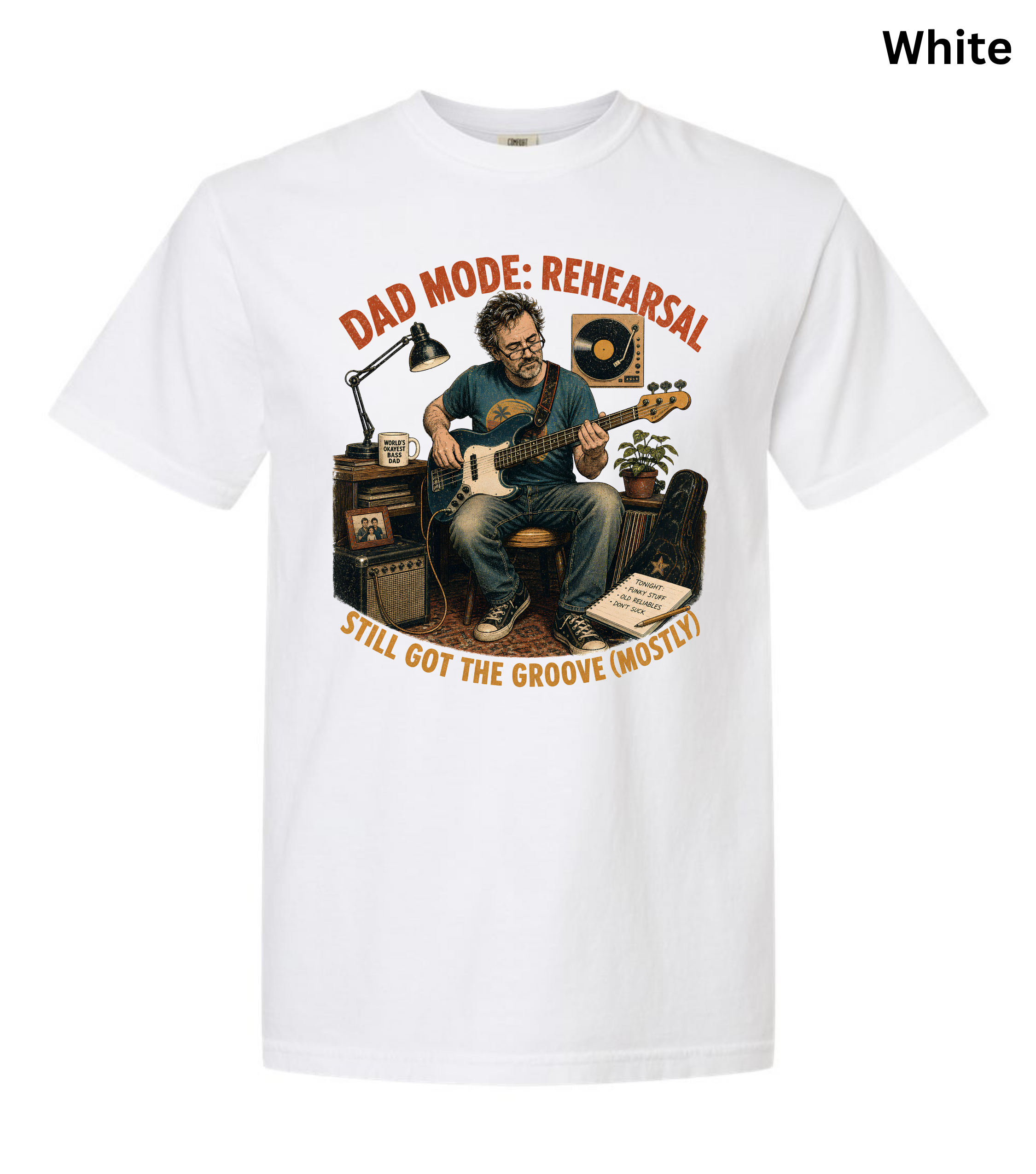 A white short-sleeve crewneck t-shirt featuring a vintage-style graphic of a man playing an acoustic guitar in a rehearsal studio. The graphic includes the text 'DAD MODE: REHEARSAL' and 'STILL GOT THE GROOVE (MOSTLY!)' in orange-brown lettering.
