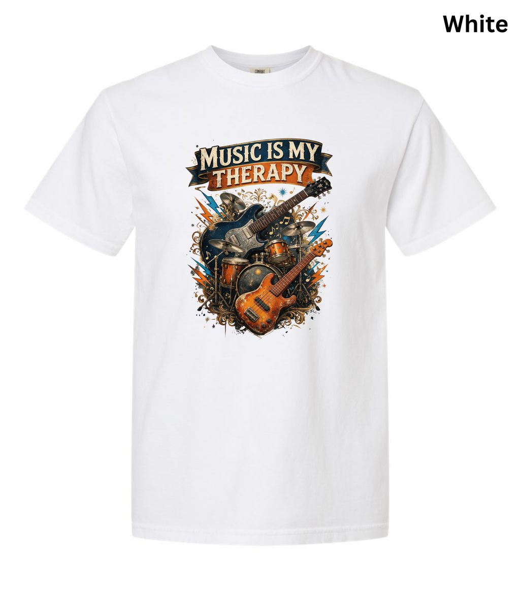 A white short-sleeve crewneck t-shirt featuring a colorful graphic print on the front with the text 'MUSIC IS MY THERAPY' above an illustration of guitars, drums, and a bass, shown on a plain white background with 'White' text in the top right corner.