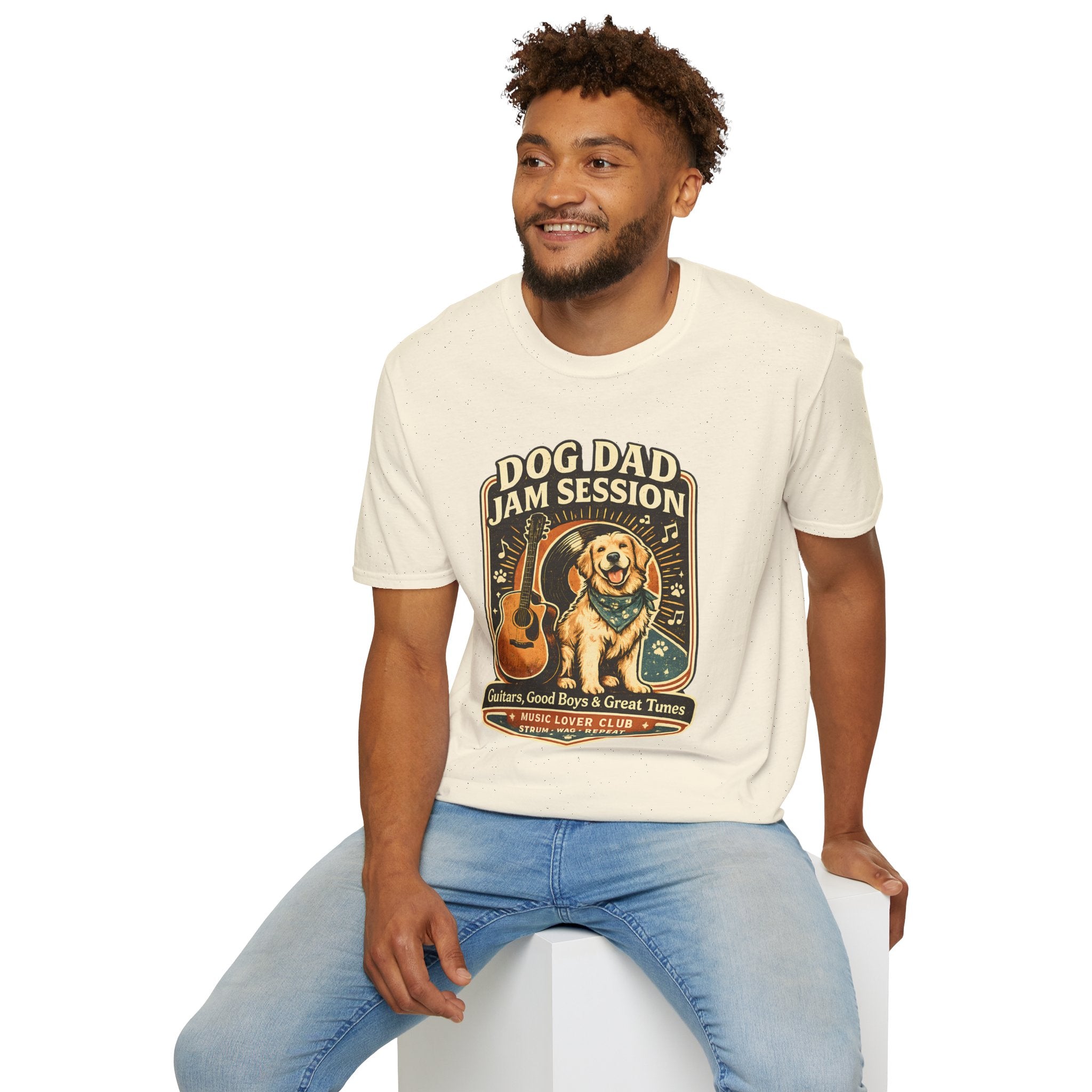 Man wearing a t-shirt with a graphic design of a character and text, sitting on a white stool against a white background.