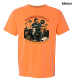 An orange short-sleeve t-shirt with a graphic print of a man playing guitar in front of amplifiers, with the text 'DAD MODE: REHEARSAL' and 'I STILL GOT THE GROOVE MUSHED!' printed around him. The word 'Melon' is written in the top right corner.