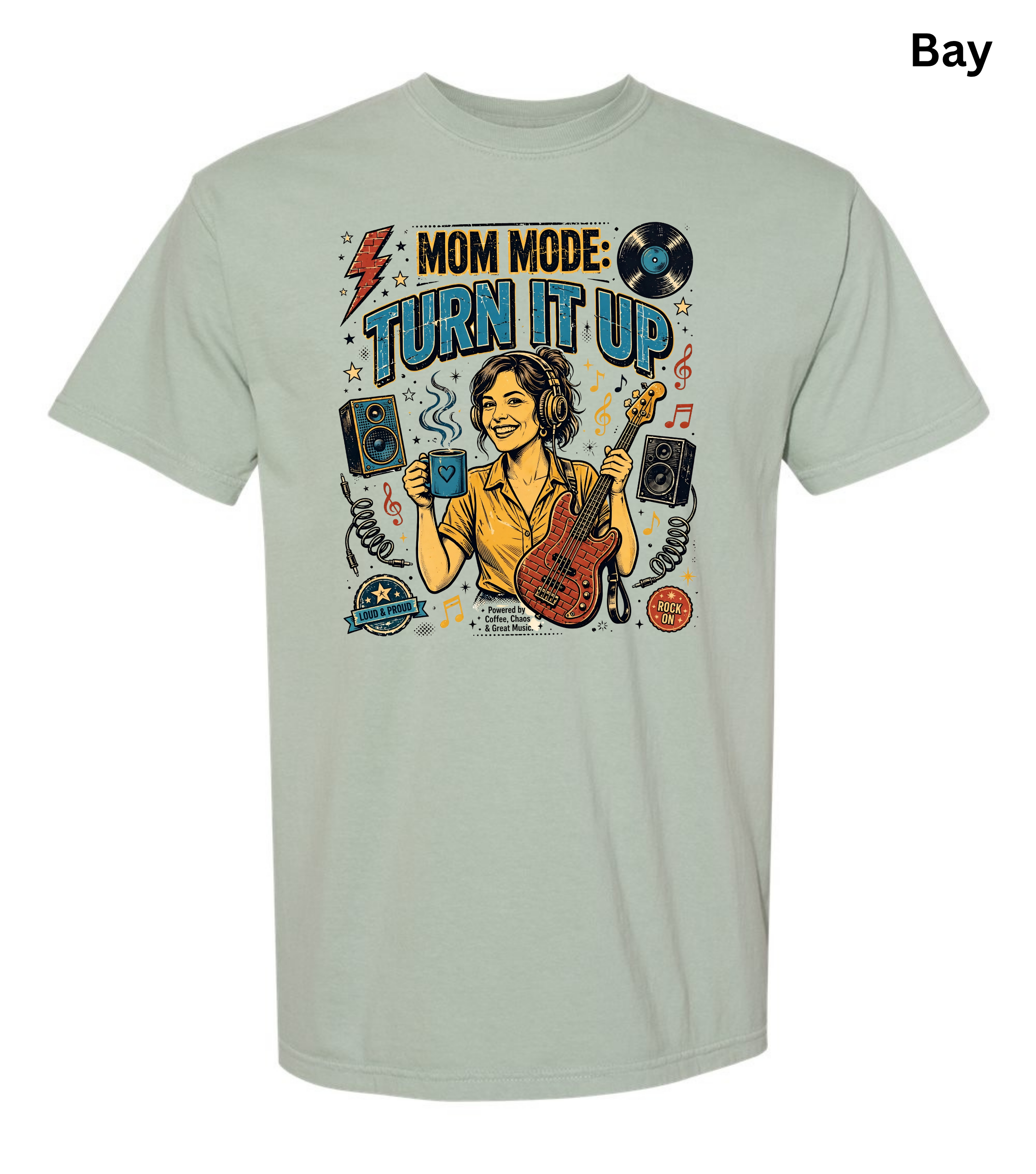 A light sage green t-shirt with a colorful graphic on the chest that reads 'MOM MODE: TURN IT UP' featuring an illustration of a woman playing guitar and holding a drink. The word 'Bay' is printed in the top right corner.