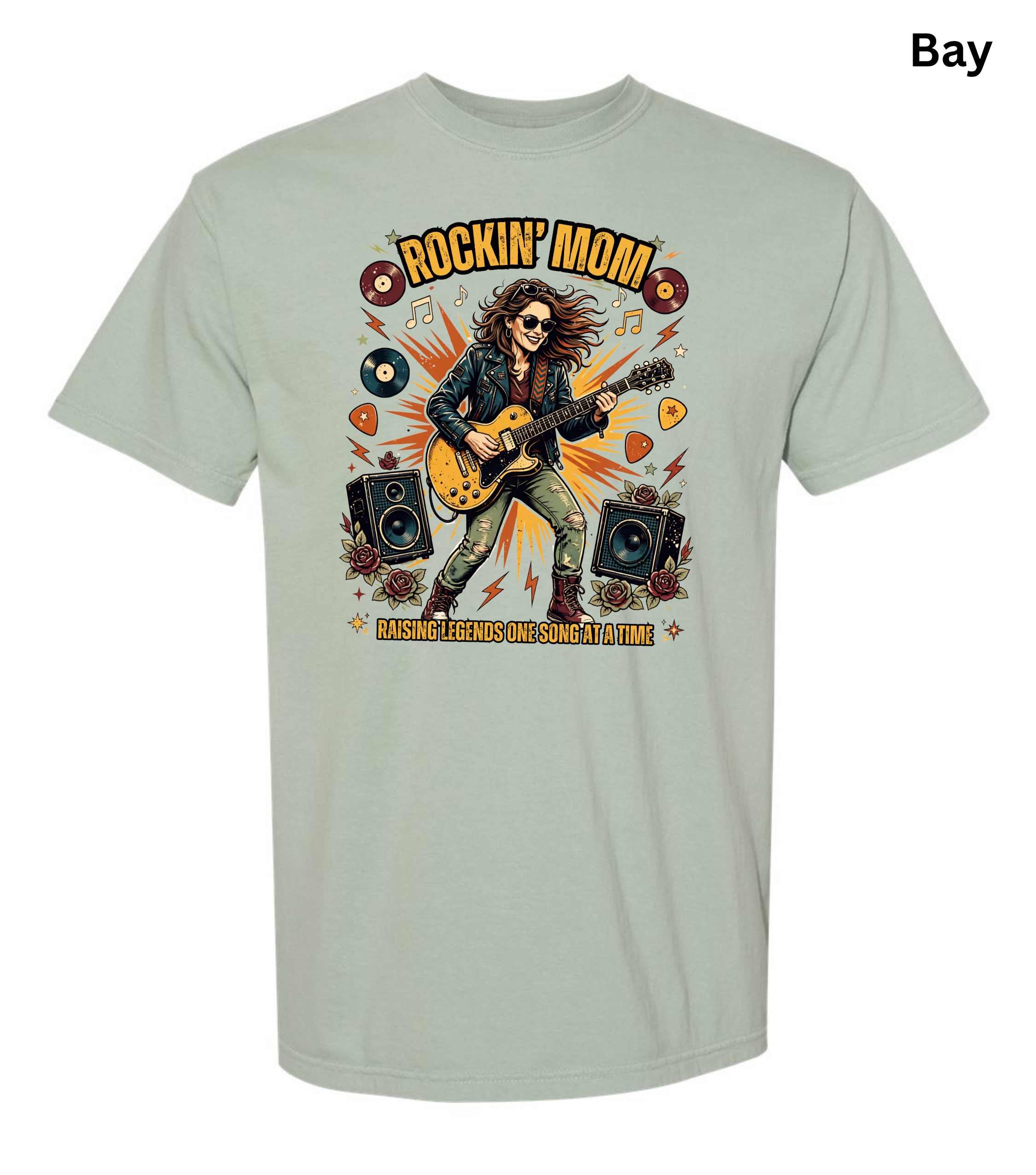 A light sage green t-shirt with a colorful graphic of a rock star playing an electric guitar, surrounded by vinyl records, speakers, and guitar picks. The text 'ROCKIN' MOM' is printed above, and 'MASHING ROCKS OUT SOONLY OUTFIT' is printed below.